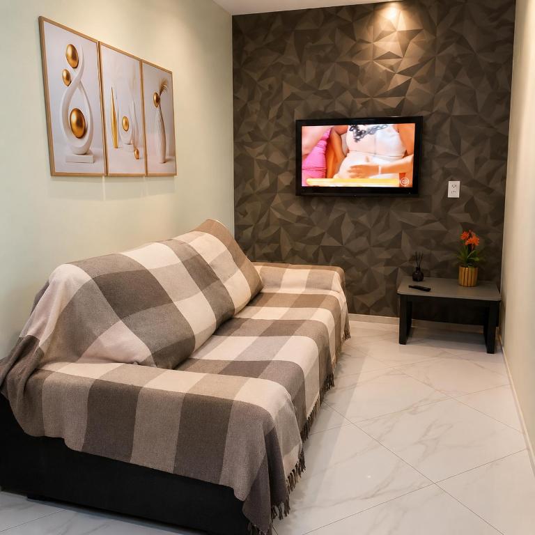 a bedroom with a bed and a tv on a wall at Apartamento 2 Quartos com Garagem e Ar Condicionado próximo do centro 3km in Cachoeiro de Itapemirim