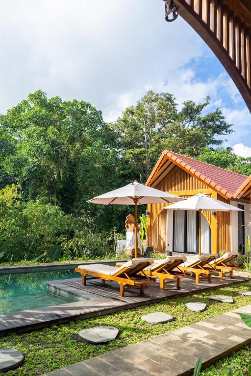 a resort with tables and umbrellas next to a pool at Jisa Sidemen in Sidemen