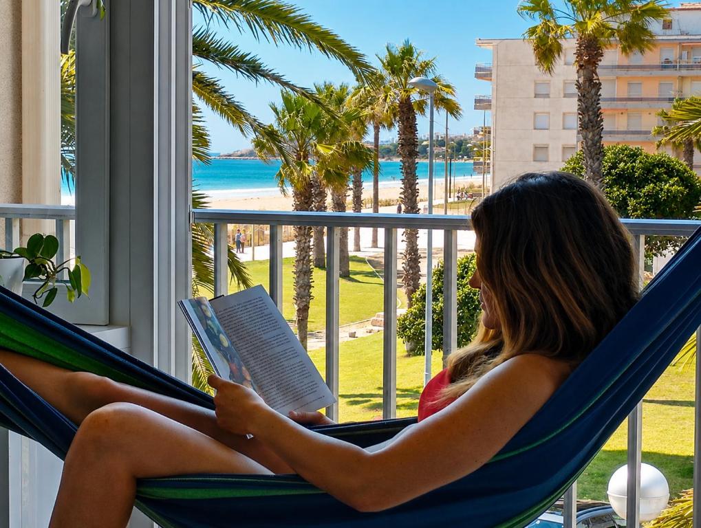 a woman sitting in a hammock reading a book at La Pineda Pisito Playero in La Pineda
