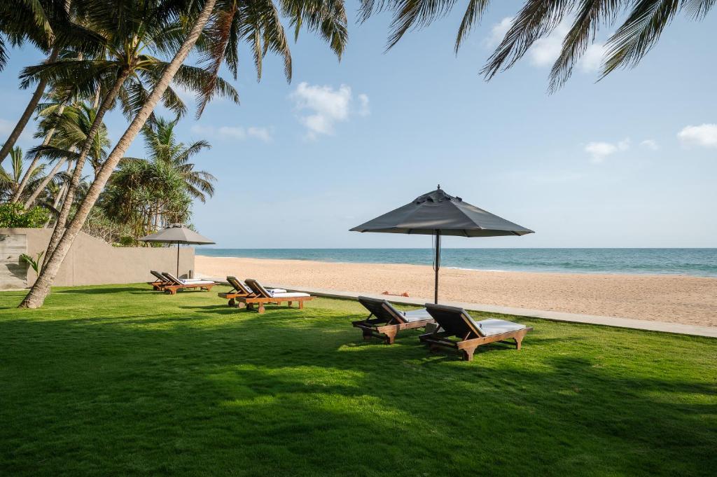 a group of chairs and an umbrella on the beach at The Coast Sri Lanka, Bentota in Bentota