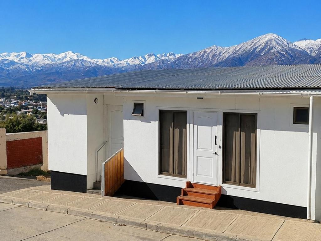 a small white house with mountains in the background at Hostal Vista Valle in Illapel