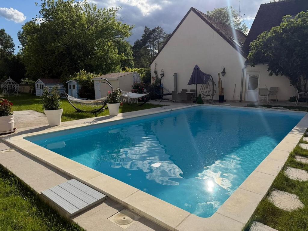 a large blue swimming pool in front of a house at Chambre privée Moret Sur Loing in Moret-sur-Loing