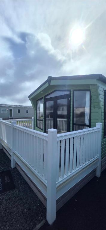 a green house with a white railing on a deck at LJ Holiday Let in Middleton