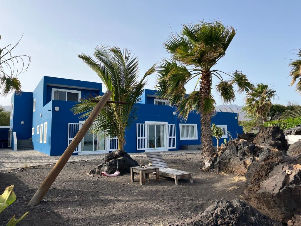 a blue house with palm trees in front of it at Cap-Azul in Porto Novo