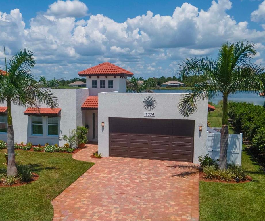 a house with a garage and palm trees at Lake Marlin Villa in Port Charlotte