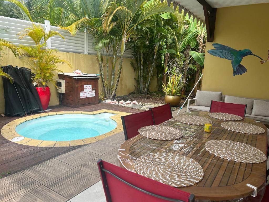 a patio with a table and a swimming pool at Maison avec piscine proche plage in Les Trois-Îlets