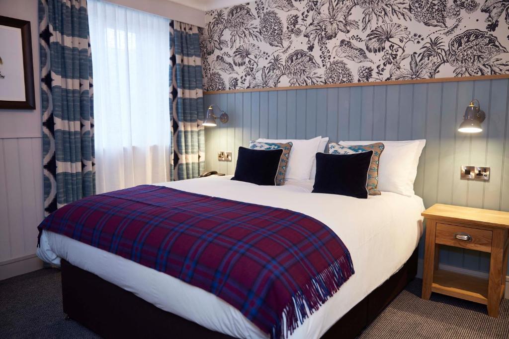 a bedroom with a large bed with a plaid blanket at Greswolde Arms by Chef & Brewer Collection in Solihull