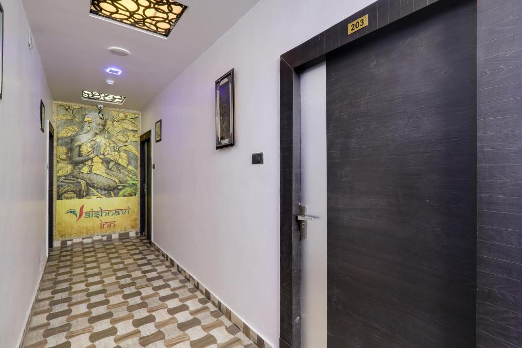 a hallway with a black door and a checkered floor at Townhouse Hotel Vaishnavi Inn in Lucknow