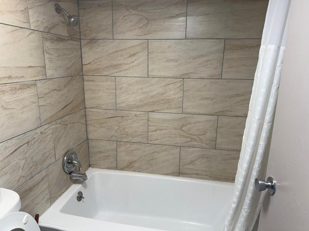 a bathroom with a shower with a white bath tub at Crown Lodge in Kansas City