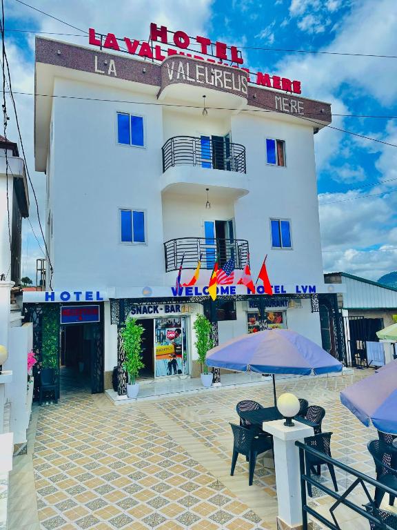 a hotel with tables and umbrellas in front of it at hotel la valeureuse mère in Yaoundé