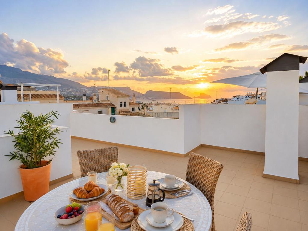 a table with food on a balcony with the sunset at Penthouse with Sea and Mountain view by NRAS in Altea
