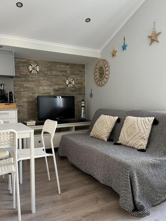 a living room with a bed and a table and a television at NEW - Casa Rocha in Sesimbra
