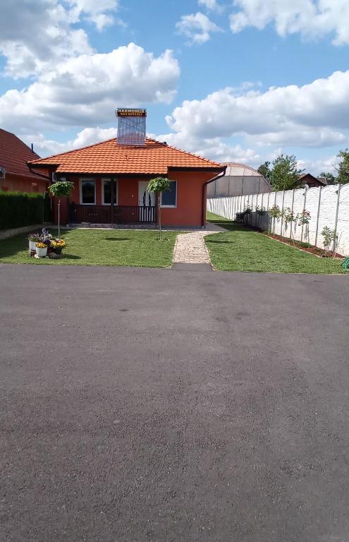 a house with a red roof and a fence at Harmonija in Palić