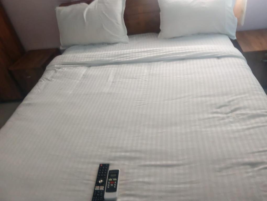 a white bed with two remote controls on it at coastal charm in Chennai