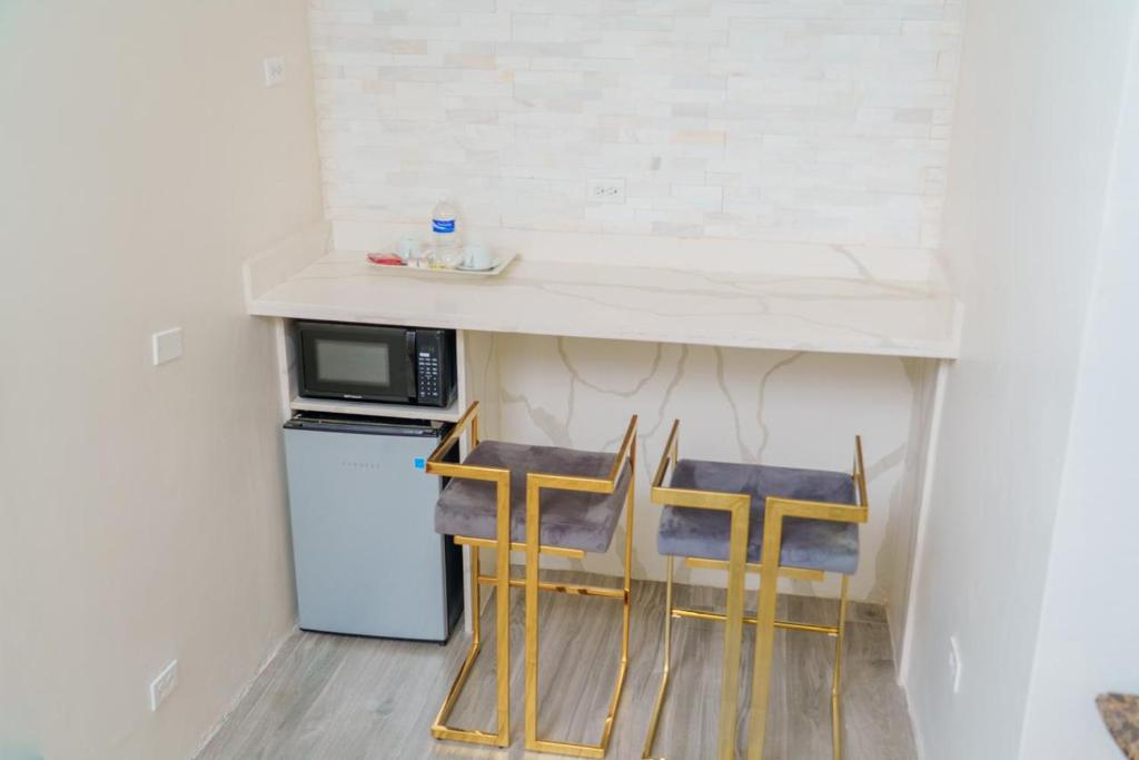 a kitchen with three chairs under a counter with a microwave at Royale Jazz Hotel in Kingston