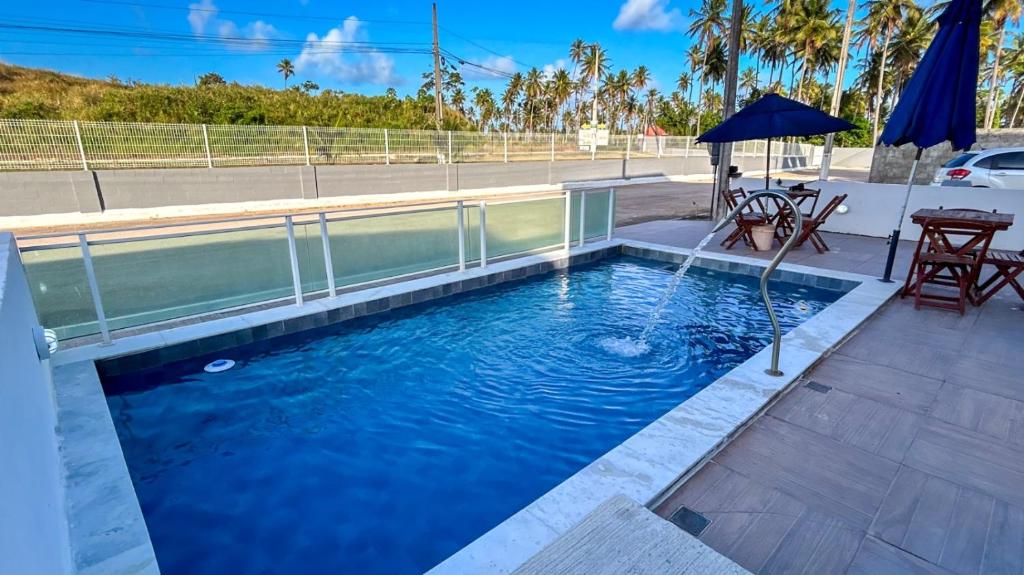 a swimming pool with a table and an umbrella at Flats Praia de Gravatá in São José da Coroa Grande