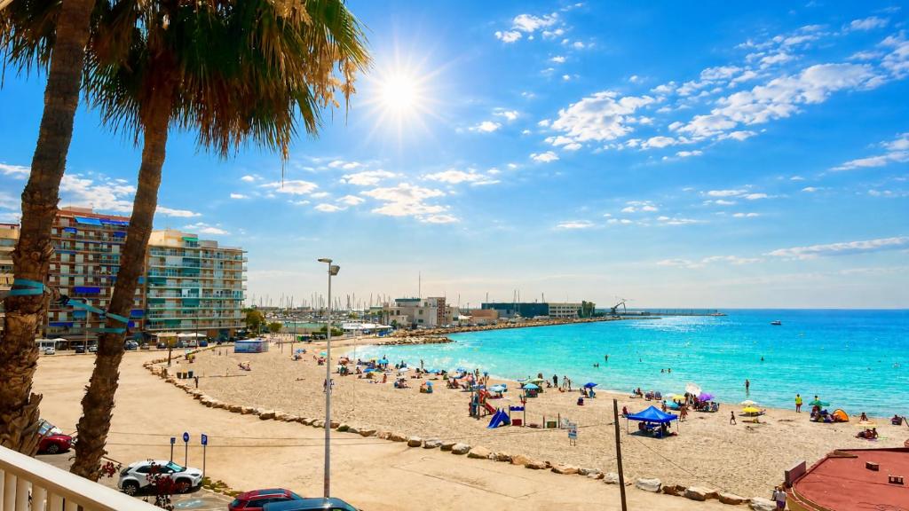 a beach with a crowd of people and the ocean at Mar, terraza y parking in Santa Pola