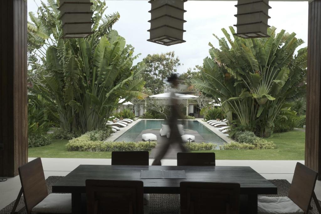 a woman walking in a dining room with a table at YŪN Uluwatu in Uluwatu
