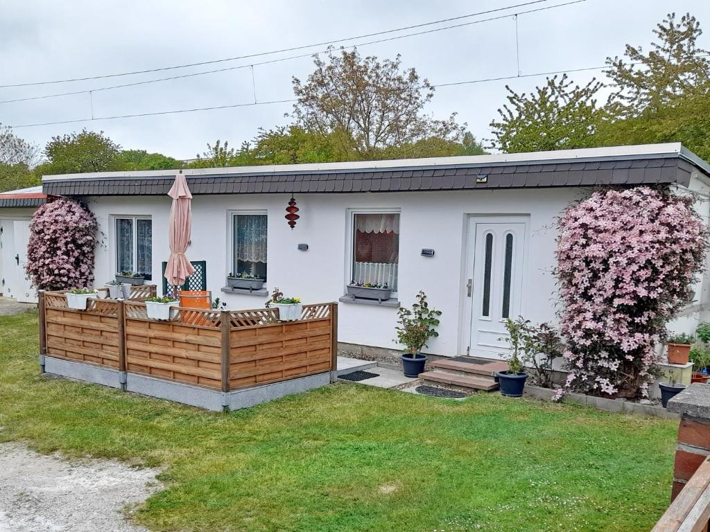 a small white house with a fence and flowers at Ferienhaus Figelski in Sassnitz