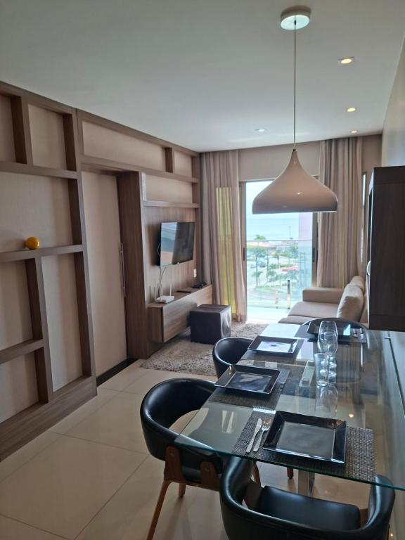 a living room with a glass table and chairs at Brisa Calma Premium Flat - PontaNegra in Natal