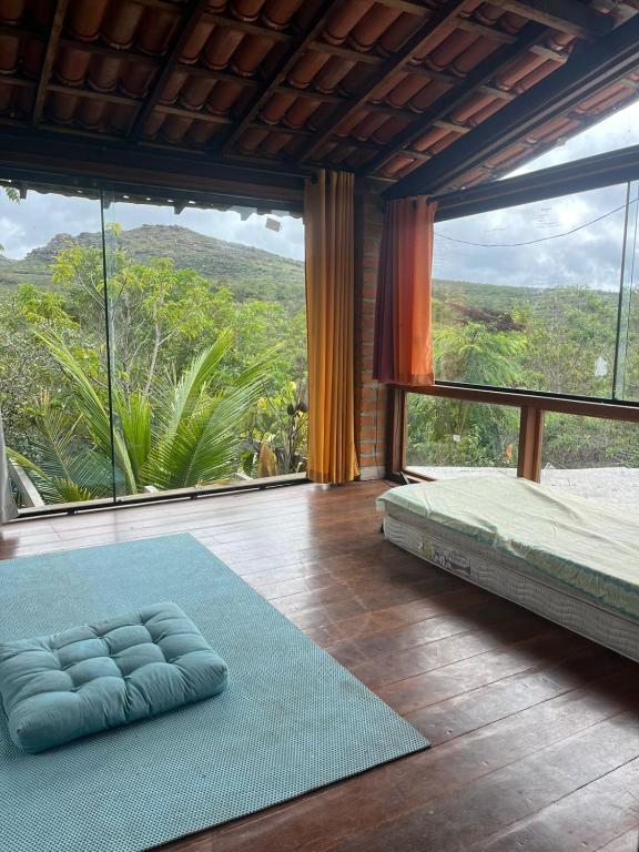 a bedroom with a bed and a large window at Golden refuge in Vale do Capão in Passagem