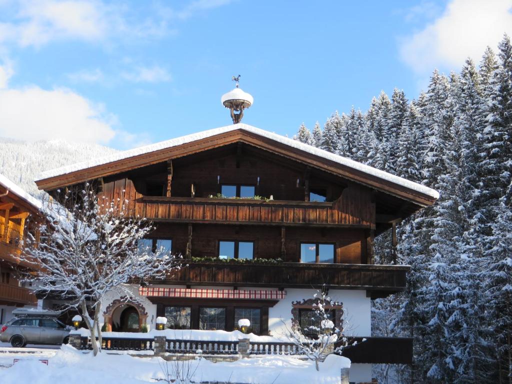 a log cabin in the snow with trees at Pension Mühlbachhof in Alpbach