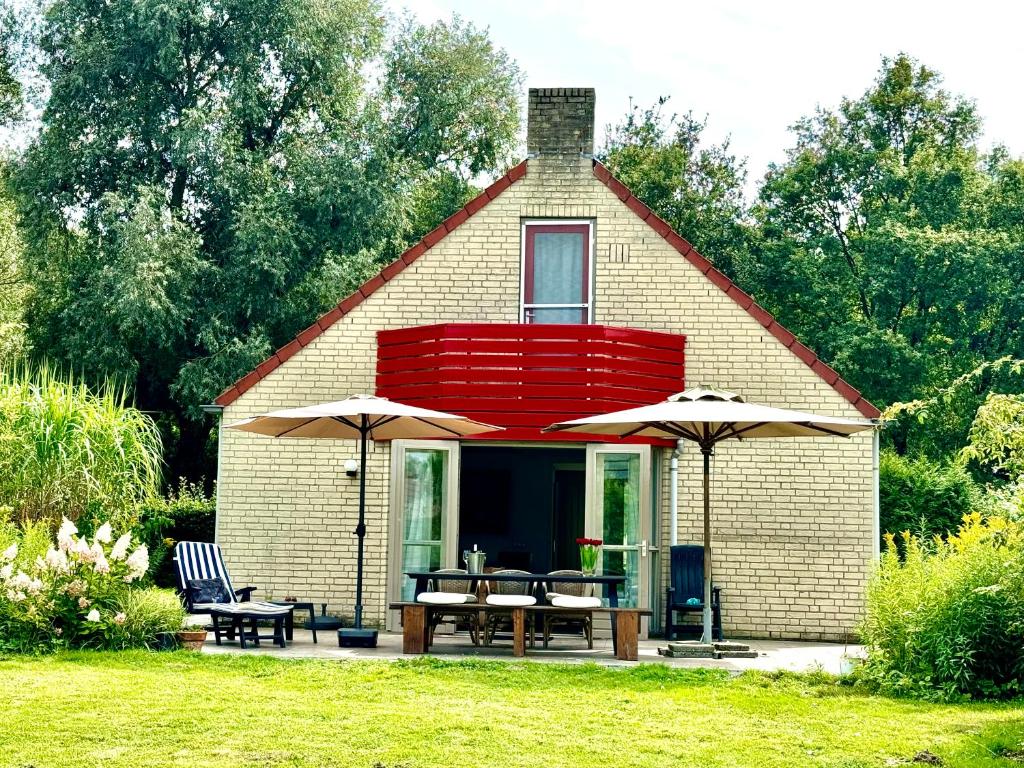 a small house with tables and chairs and umbrellas at 5 - Persons Lakeside 41 Bungalow in Ewijk
