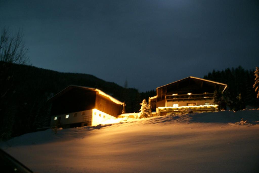 a couple of buildings in the snow at night at Pension Chalet Bergseegut in Wagrain