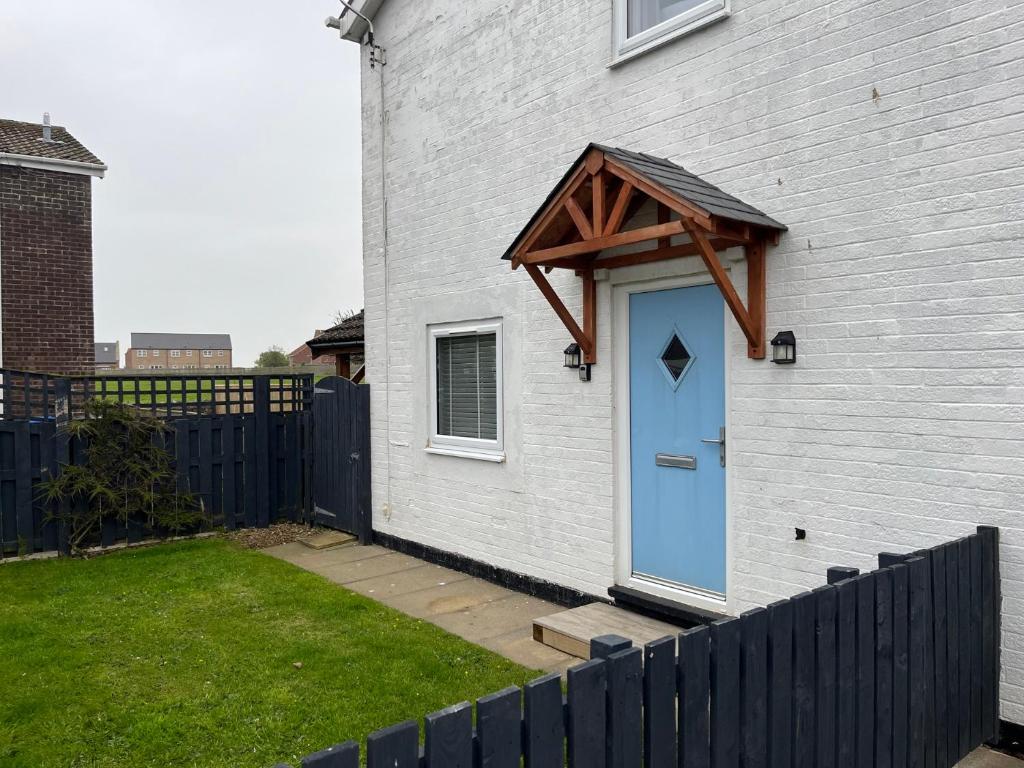 a blue door on a white house with a fence at 22 Longstone Park in Chathill