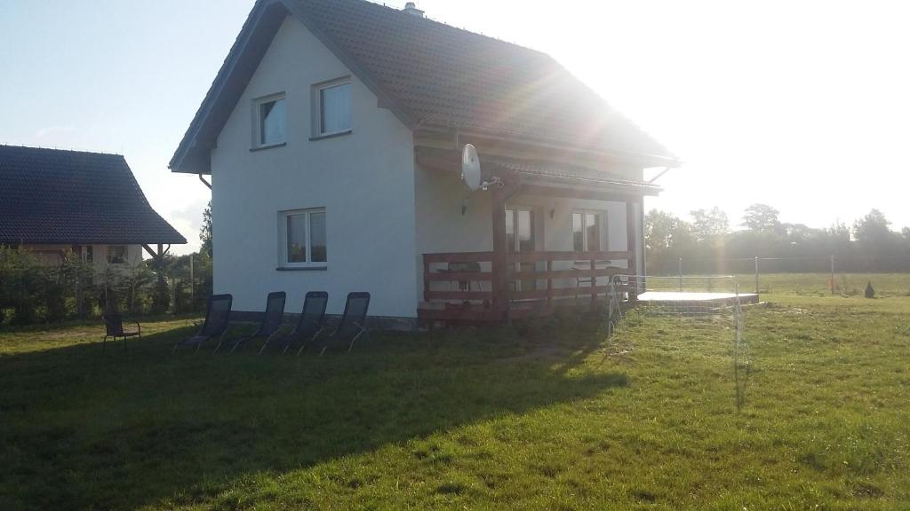 een wit huis met stoelen in een veld bij Dom Nad Morzem Kinga in Smołdziński Las