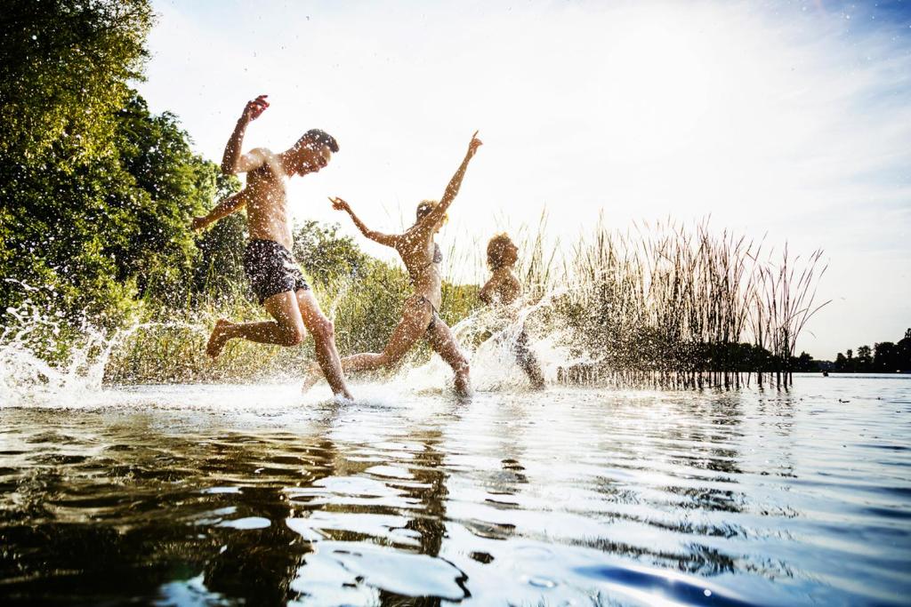 three boys are jumping into a body of water at SeeLaVie - Tiny Houses am Mattsee in Mattsee