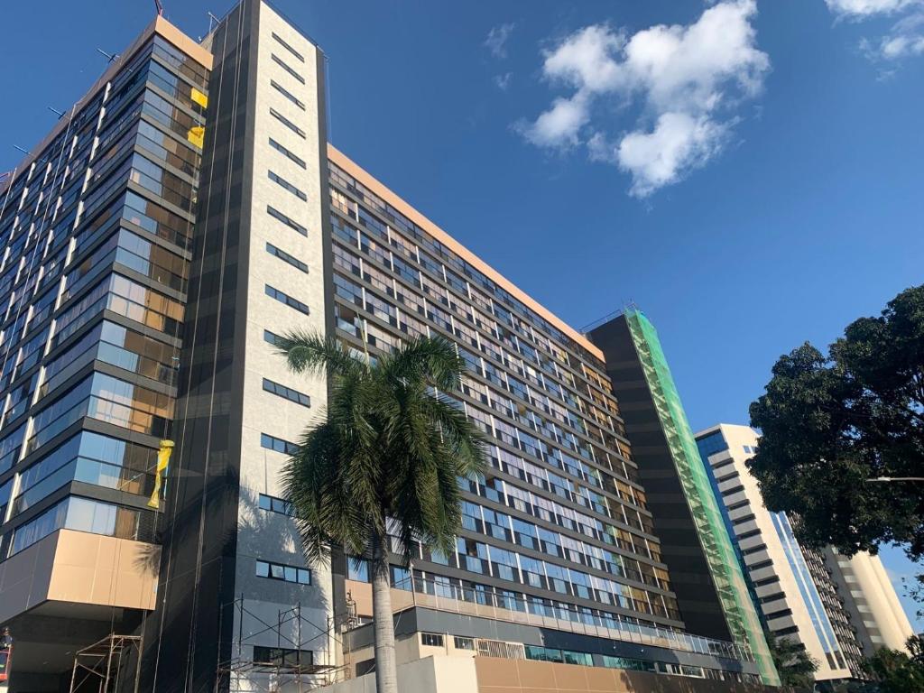 a tall building with a palm tree in front of it at MIX APART Hotel in Brasília