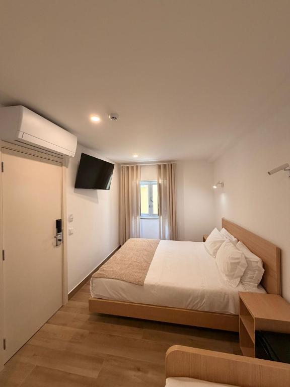 a bedroom with a large bed and a television at B&B Berlenga 4 in Nazaré