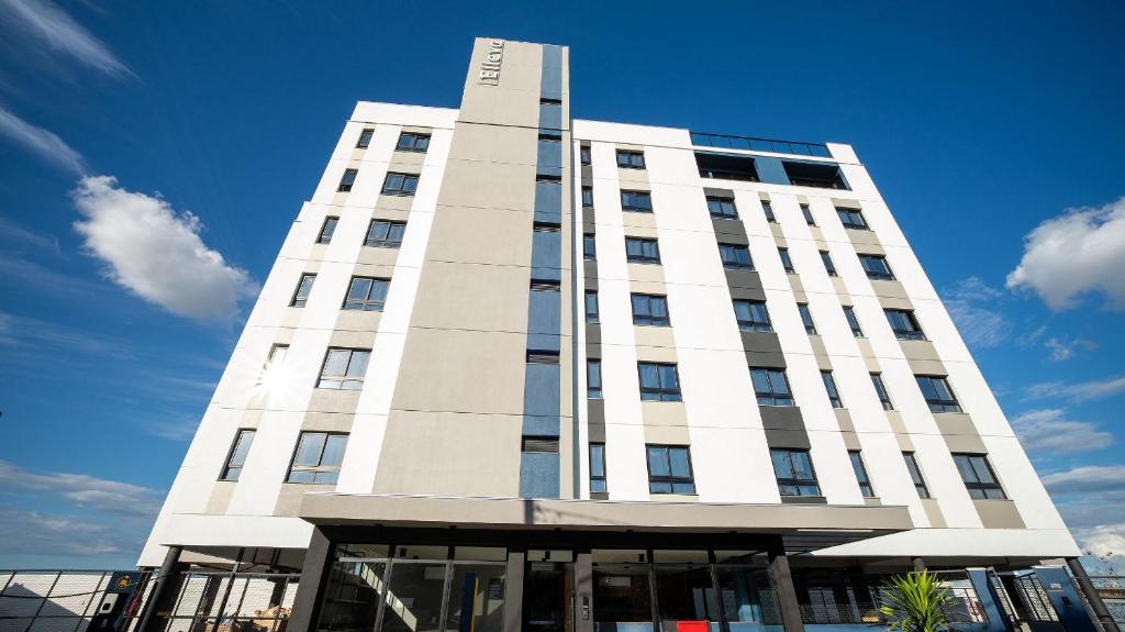 a tall white building with a blue sky in the background at ELLEVA STUDIOS | Studio moderno com coworking e rooftop em Sinop in Sinop