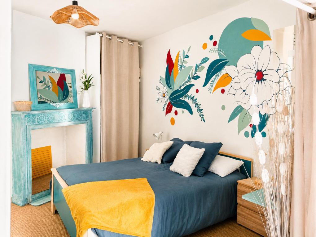 a bedroom with a blue bed with flowers on the wall at Appartement bleu in Eymoutiers