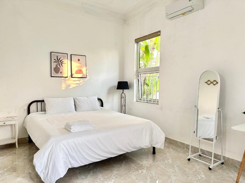 a white bedroom with a bed and a window at Villa Rosa HueS in Thôn An Hòa