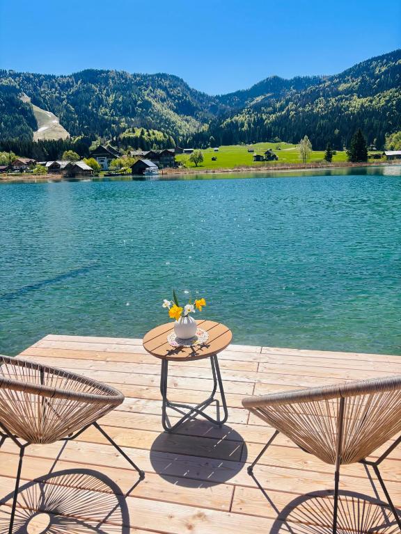 a table with a vase on it next to a lake at Der Kaerntnerhof am Weissensee, SeeHotel & SeeApartments direkt am See in Weissensee