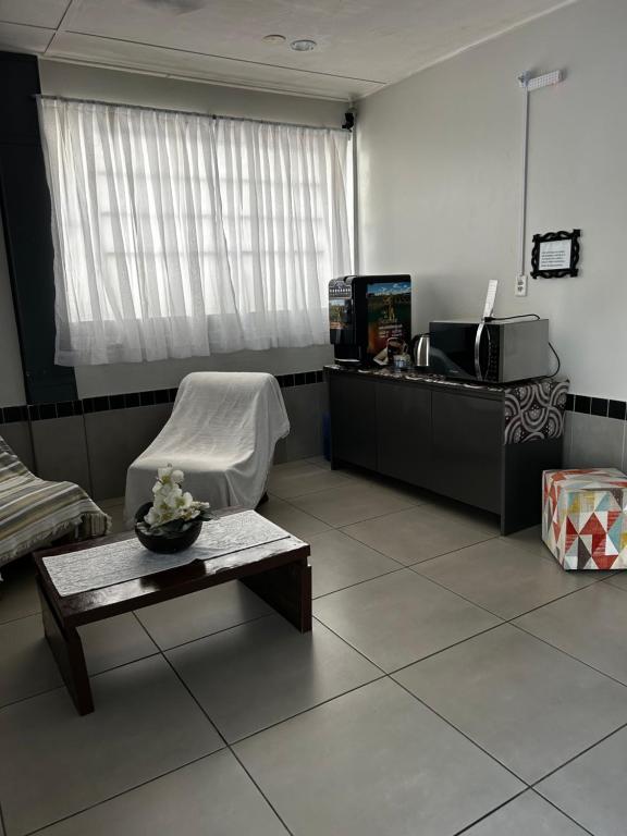 a living room with a chair and a table and a window at HL Hotel in Pelotas
