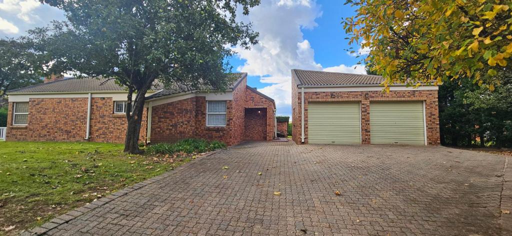 a brick house with two garage doors on a driveway at Applegate lodge in Clarens