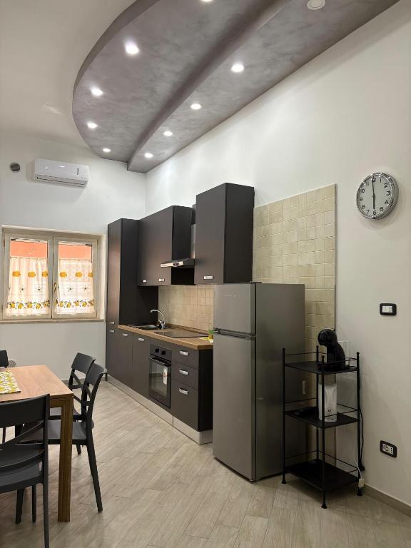 a kitchen with a refrigerator and a table and a clock at B&B Mamie in Bellizzi