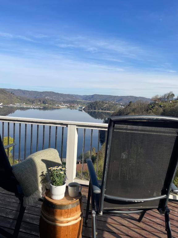 a balcony with a chair and a view of a lake at Apartment with great sunset view! in Lyngdal