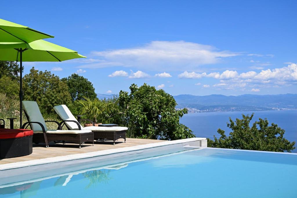 a swimming pool with two chairs and an umbrella at Villa Yari-Dog Friendly, Private Jaccuzzi&Sauna,Shared Infinity Pool, Sea View in Lovran