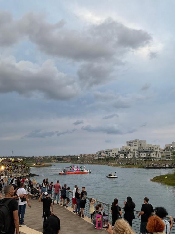 a group of people standing on a pier with a boat in the water at באר מרים in Ashkelon