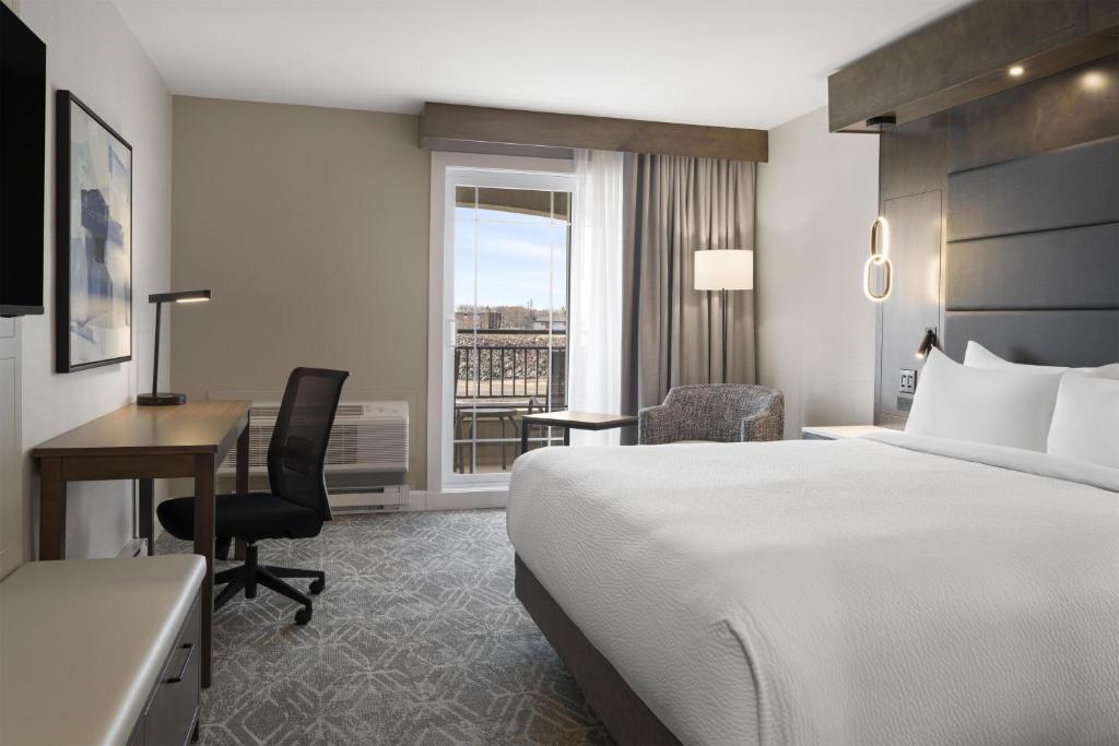 a hotel room with a bed and a desk and a window at Best Western Premier Hotel Aristocrate in Quebec City