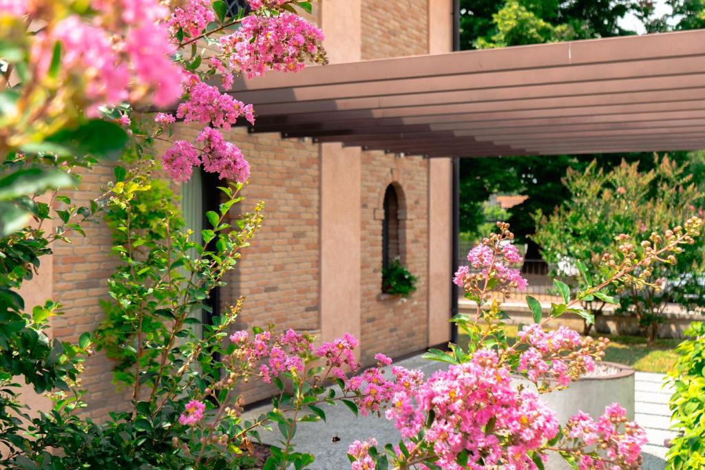 a garden with pink flowers in front of a brick building at Dimora al Glicine in Sernaglia della Battaglia