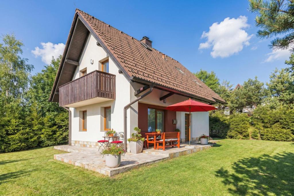 a small white house with a red umbrella at Sunny Weekend Sauna House - Happy Rentals in Preserje