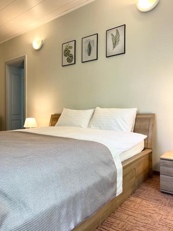 a bedroom with a bed and three pictures on the wall at ThaiThanee COZY HOUSE in Palanga