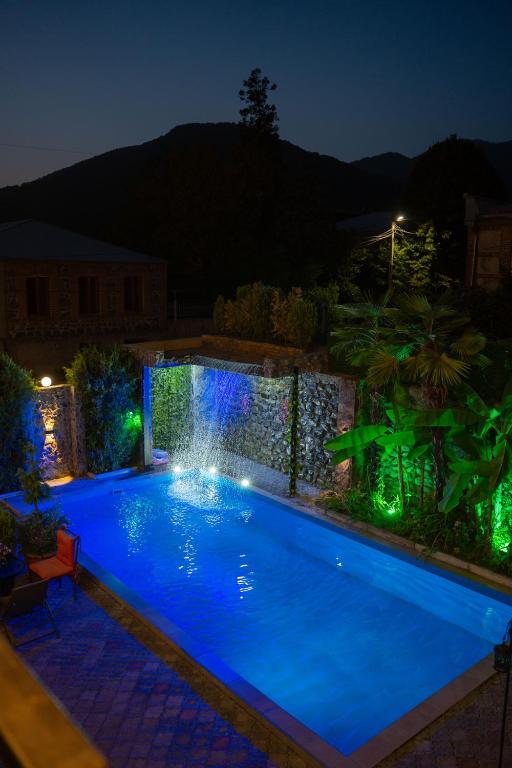 a swimming pool with a waterfall in a backyard at night at Hotel and Restaurant "VILLA GIVISI" in Lagodekhi