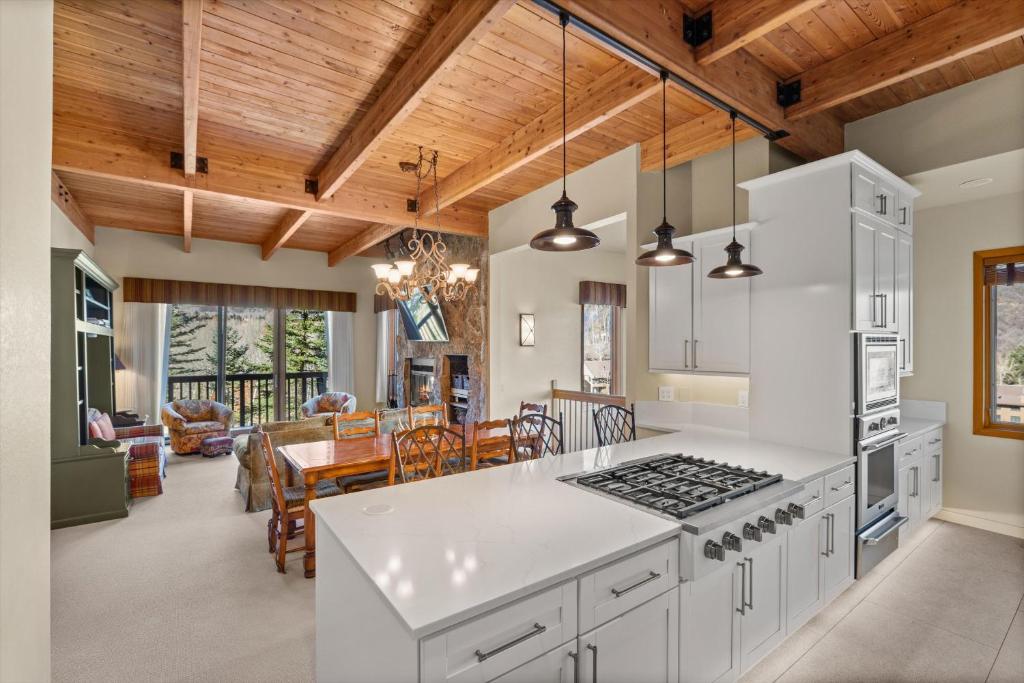 a kitchen with white cabinets and a dining room at 229 #35 by SkyRun Aspen in Snowmass Village