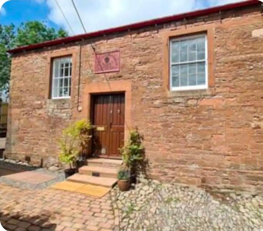 a brick house with a brown door and windows at Chapel House Accommodation in Culgaith